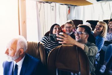 Happy travelers taking selfie photo in bus.