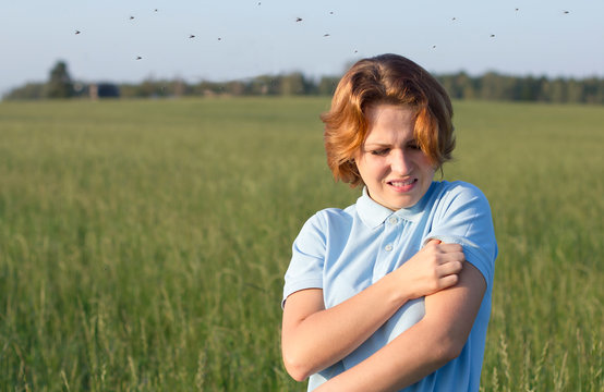Girl suffers from insect bites. Itching of skin diseases using the hand-scratching. Insect attack. Mosquitoes fly around a woman.