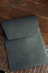 black leather case for tablet. eco leather case on a wooden background