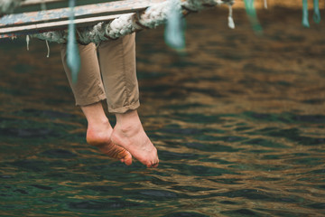 crop picture man sitting at suspension bridge put legs in sea water