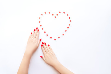 Hands of a beautiful well-groomed woman with red nails on a white background. Nail polishing in white.