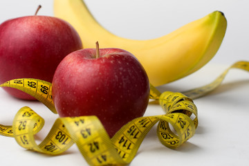 Fresh fruit and measuring tape on a white background, the trend of healthy living and fighting obesity.