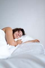 young pretty caucasian woman sleeping in bed with white sheets