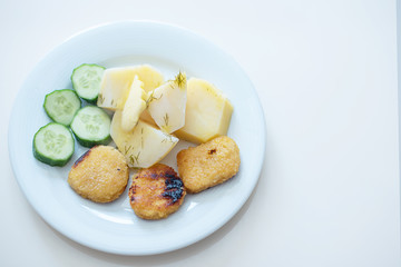 boy eating simple and cheap food for children - nuggets, cucumbers and potatoes