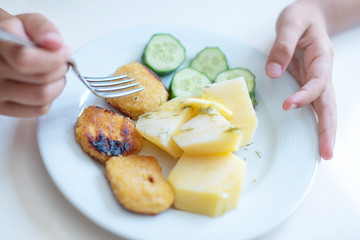 boy eating simple and cheap food for children - nuggets, cucumbers and potatoes