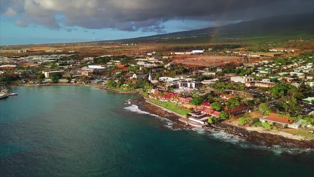 Aerial view of the city of Kailua Kona during sunset with stormy sky and rainbow on the background, Big Island, Hawaii. Camera orbits clockwise