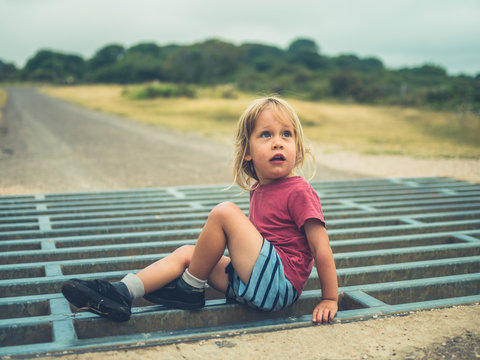 Little toddler playing on a cattle grid
