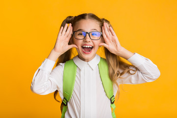 Elementary Student Girl Shouting Holding Hands Near Mouth, Yellow Background