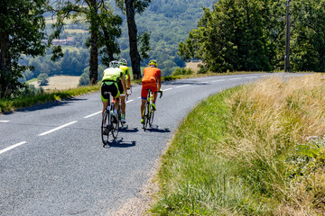 Three cyclists ride along a beautiful mountain road. Sport and active life concept.