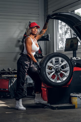 Obraz na płótnie Canvas Professional female auto mechanic is fixing broken car at auto workshop near window.
