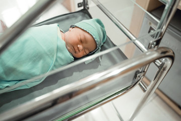 Newborn baby laying in crib in the hospital