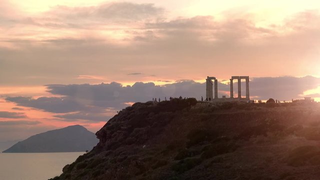 Amazing Temple of Poseidon on Cape Sounion above Aegean sea, Greece. Colorful sunset. Ancient stone ruins of iconic construction with columns and stairs. Mythology of hellenic civilization