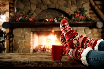 Woman legs with christmas socks and fireplace in home interior 