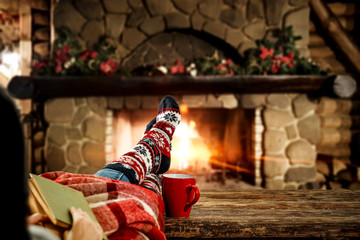 Fototapeta na wymiar Woman legs with christmas socks and fireplace in home interior 