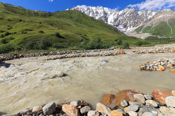 Landscape views of the Caucasus Mountains, river and villages. Peak and river Enguri. Georgia. Summer. 2019