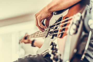 A man plays a bass guitar close-up. Toned photo.