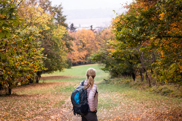 Fototapeta premium Hiking woman with backpack enjoying trek in autumn forest