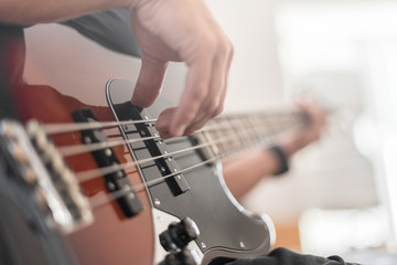 A man plays a bass guitar close-up. Toned photo.