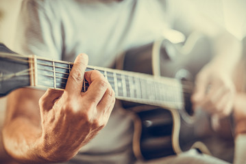 A man plays the guitar close-up. Toned photo.