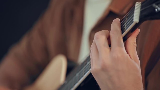 cropped view of man playing acoustic guitar at home