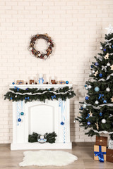 Decorated fireplace near christmas tree on brick wall background
