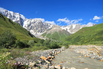 Landscape views of the Caucasus Mountains, river and villages. Peak and river Enguri. Georgia. Summer. 2019