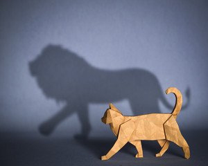 Concept of hidden potential. A paper figure of a cat that fills the shadow of a lion. 3D illustration
