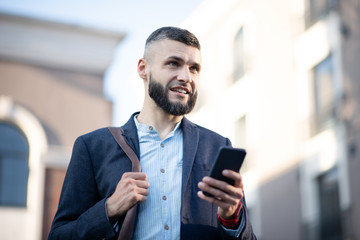 Businessman holding smartphone while standing outside
