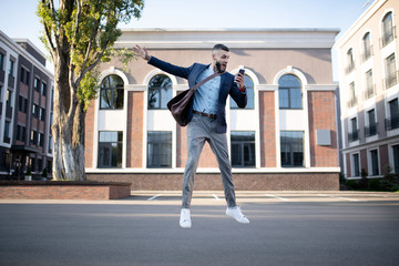 Obraz premium Businessman holding phone jumping while feeling emotional