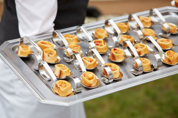 Waiter serving food. Tray with individual portions. Appetizers. Banquet food. Gastronomy. Haute...