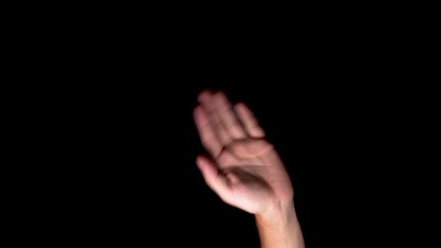 Small Hand isolated on a black background waving at the camera