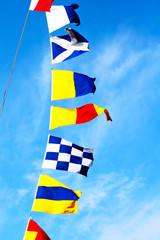 Marine signal flags set on a mast against of the blue sky.