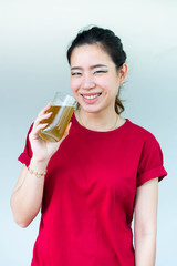 Woman in red shirt holding a glass of green tea and has a large smile