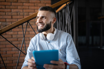 Smiling man holding little tablet while having little break