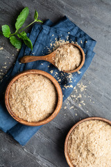 Dietary supplement, unfortified nutritional yeast flakes in a wooden bowl and scoop