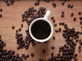 cup of coffee with beans on wooden background