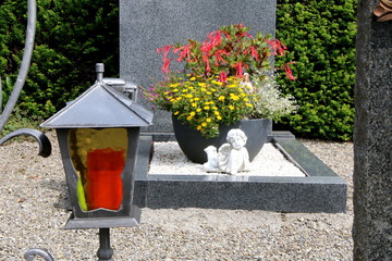 Am Friedhof, Grabgestaltung, Grab mit Sommerblumen, Engel und Madonna, im Vordergrund eine Grablaterne