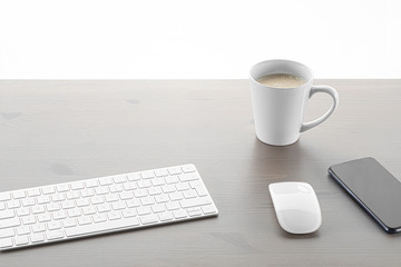 Coffee on a wooden table with a white background with a computer keyboard a mouse and a mobile phone on the table. technology