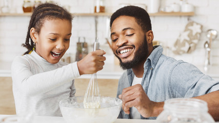 African man teaching his girl how to make dough