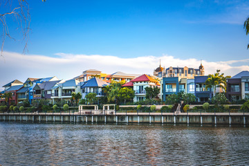 Fototapeta premium Wide panoramic view of Emerald Lakes residences across the lake, on a blue sky background during a beautiful sunset. Gold Coast, Australia.