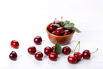 Sweet cherries in bowl on white wooden table