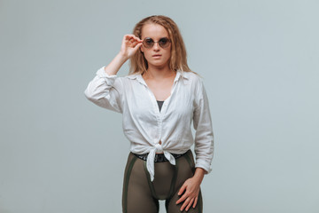 Girl in white shirt and round glasses on grey background