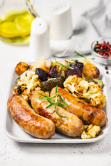 Baked vegetables and sausages. Selective focus, space for text.