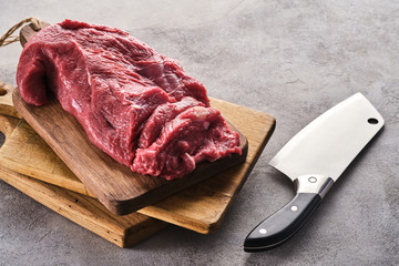 Fresh raw meat beef on a wooden board and a butcher's knife.