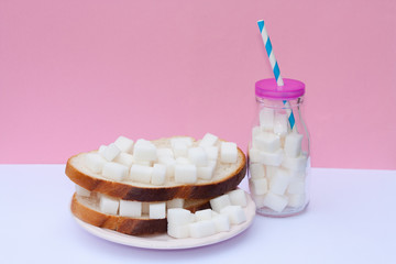 Sandwich with sugar and bottle full of sugar cubes. Too much sugar and unhealthy food concept.