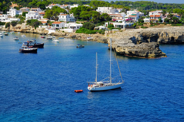 View on white boats, the beach and village Alcaufar on Menorca.