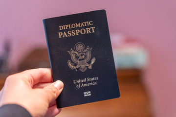 Hand holds up black Diplomatic Passport for the United States of America