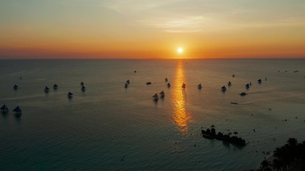 Colorful sunset above the sea surface with sailing yachts, aerial view Boracay, Philippines. Reflected sun on a water surface. Sunset over ocean. Seascape, Summer and travel vacation concept