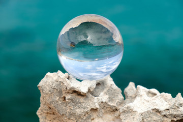 Crystal ball on the rock on the blue background.
