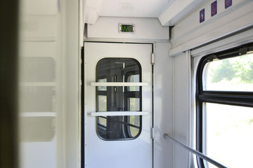 Toilet door in a train with an electronic wc sign with selective focus and blurred background. Passenger train inside with closed lavatory door. Train wagon inside. Empty train corridor with wc icon